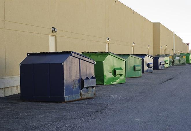 a construction worker unloading debris into a blue dumpster in Chowchilla, CA